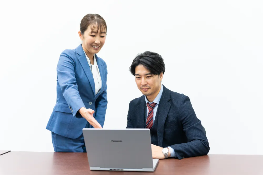 先輩に教わりながらPC作業する社員